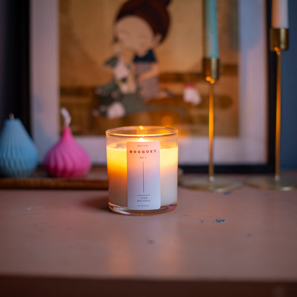 Lit Bouquet candle by Meet Haus on a wooden surface with decor and artwork in the background.