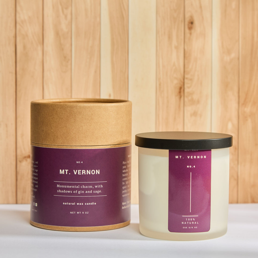 Frosted glass candle labeled “MT. VERNON” beside its kraft tube packaging; deep plum label reads: “Monumental charm, with shadows of gin and sage.