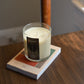 An unlit Meet Haus Forest No. 21 soy candle rests on a modern book with a geometric cover, placed on a wooden table beside a window, combining intellectual charm with a touch of nature.