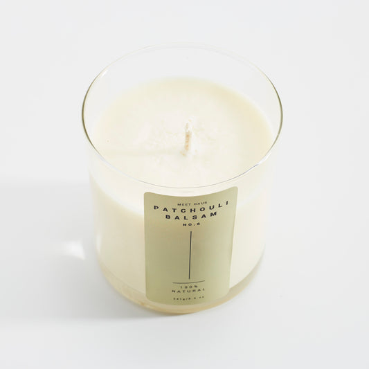 Our Patchouli Balsam candle on a neutral background showing the jar and the smooth wax on top