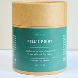 Meet Haus Fells Point soy candle, a Baltimore neighborhood scent: front of the kraft paper tube box, green band reading anchored in port, sharpened in sea salt and dry cedar, natural wax candle, net wt 9 oz.