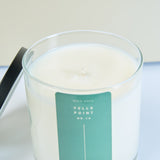 Meet Haus Fells Point soy candle, a Baltimore neighborhood scent: overhead close view of the lid-off 9 oz jar showing smooth white soy wax and a trimmed wick, black lid leaning at left, green label below.