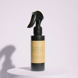 A Meet Haus Sunlit Breeze room spray bottle rotates on a clean, neutral background, showing its clear design, minimalist label, and sleek black spray top.