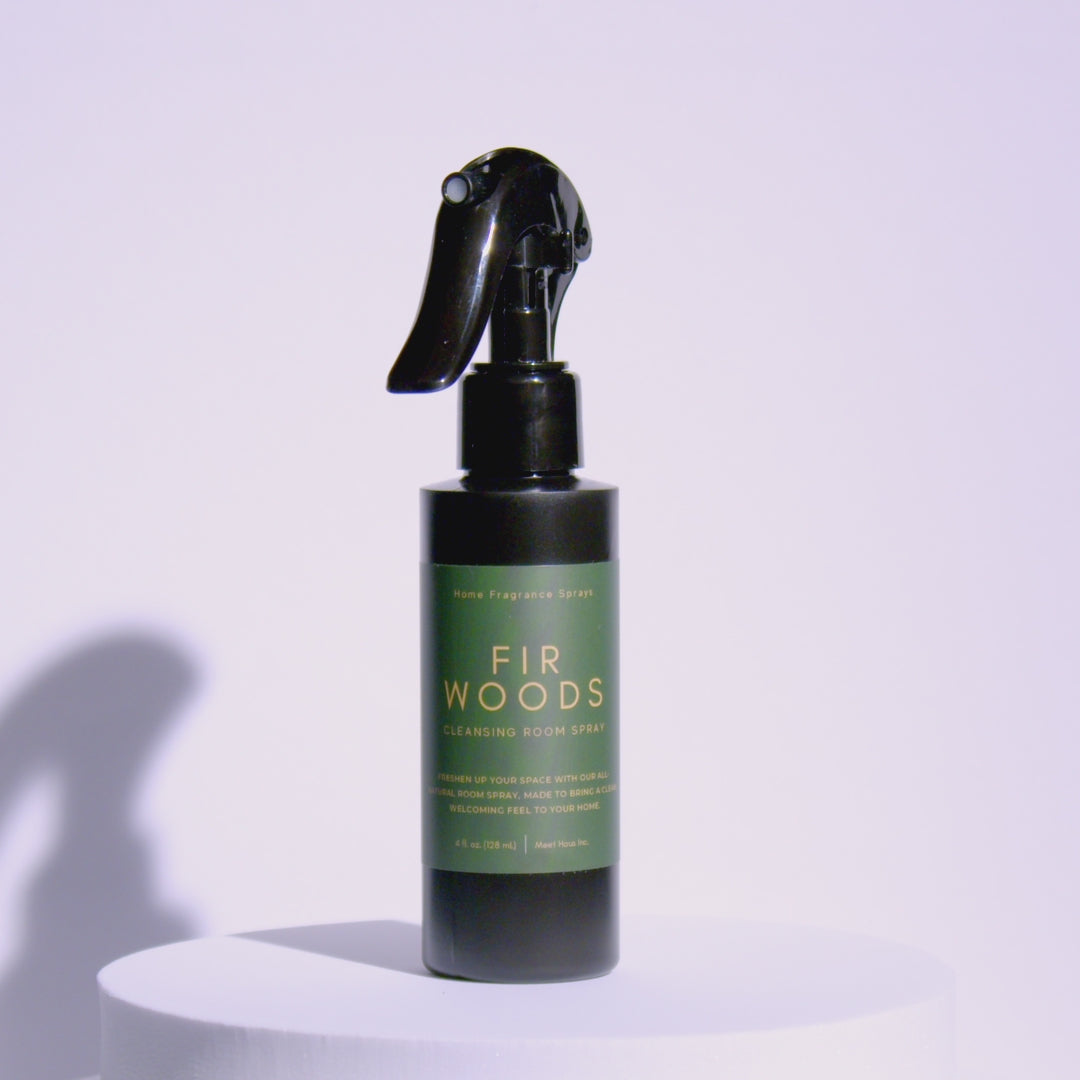 A Meet Haus Fir Woods room spray bottle rotates on a clean, neutral background, showing its clear design, minimalist label, and sleek black spray top.