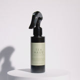 A Meet Haus Tea Haus room spray bottle rotates on a clean, neutral background, showing its clear design, minimalist label, and sleek black spray top.