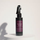A Meet Haus Rose Oud room spray bottle rotates on a clean, neutral background, showing its clear design, minimalist label, and sleek black spray top.